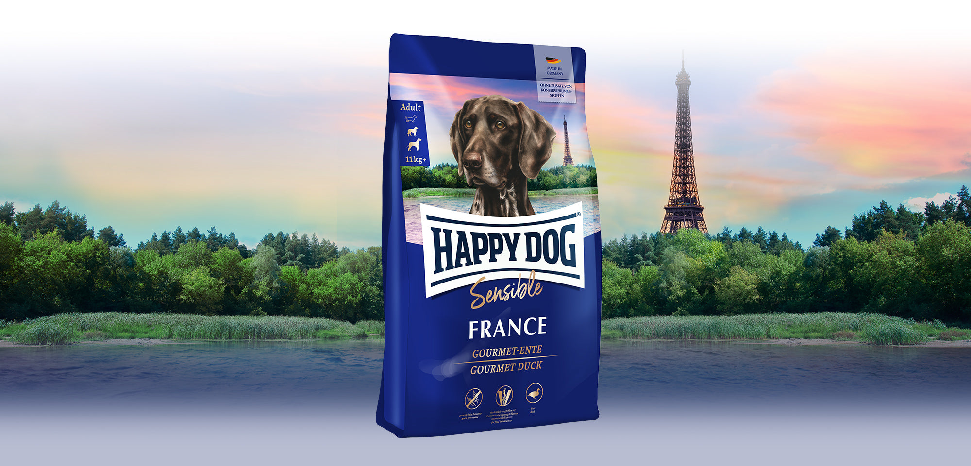 Das Hundefutter Happy Dog Sensible France vor einer französischen Landschaft mit dem Eiffelturm im Hintergrund.